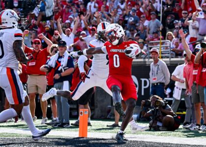 Louisville football wide receiver Chris Bell escapes defenders entering the endzone.
