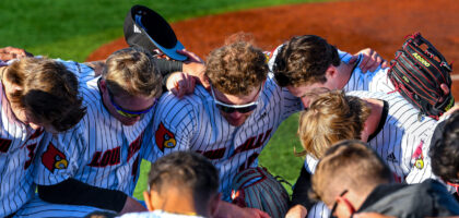 Louisville Baseball huddles together outside of the First Base Dugout Photo by Jared Anderson